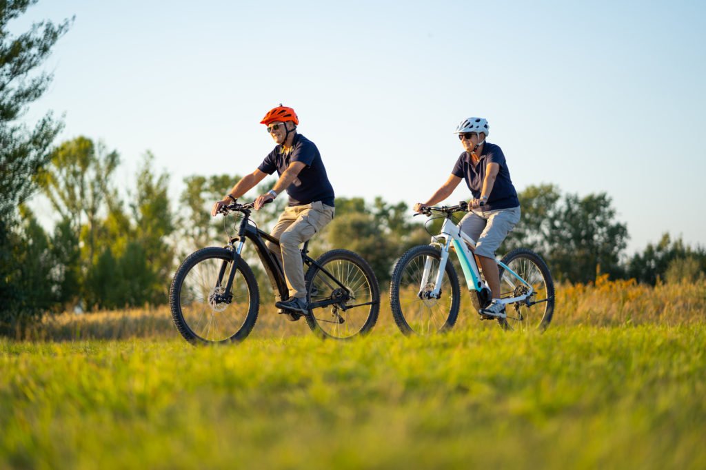 active senior couple cycling on mountain bikes through rural landscape