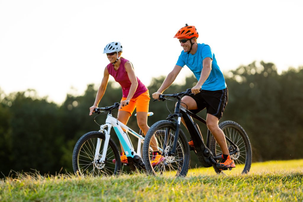 happy mature woman and man cycling together